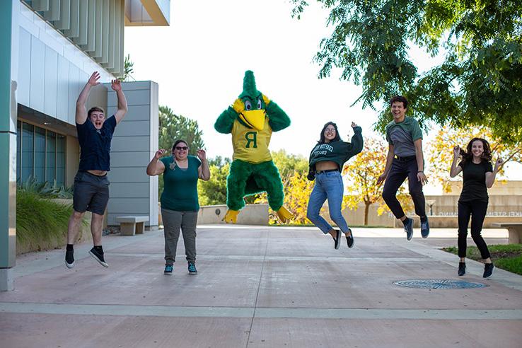 Students and roadrunner mascot jumping